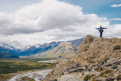 Man standing on top of a rock with scenic view of mountains against sky
