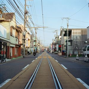 Railroad tracks by buildings in city against sky