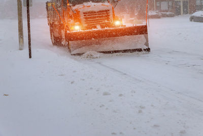 Snow covered road by illuminated street during winter