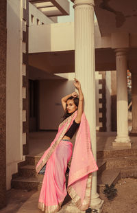 Portrait of young woman standing against pink umbrella