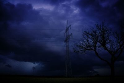 Low angle view of electricity pylon against cloudy sky