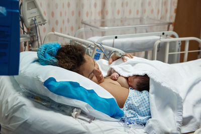 Woman with newborn body girl lying on the bed at hospital