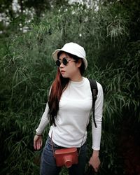 Young woman standing against plants