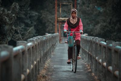 Portrait of woman riding bicycle on the small bridge 