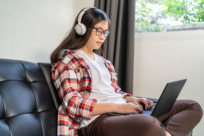 Young woman using phone while sitting on sofa