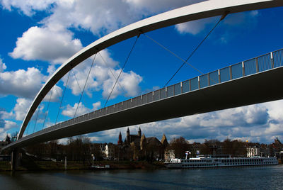 Low angle view of bridge over river against cloudy sky