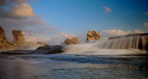 Scenic view of waterfall against sky