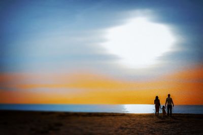 People on beach against sky during sunset