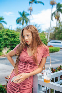 Portrait of young woman standing against trees