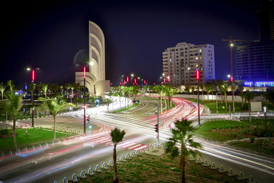 Light trails on street amidst buildings in city at night