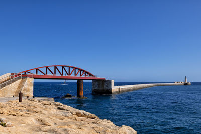 View of bridge over sea against clear blue sky