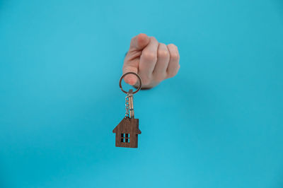 Cropped hand holding key against blue background