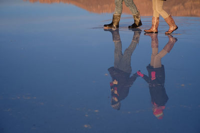 Reflection of couple walking on shore at beach