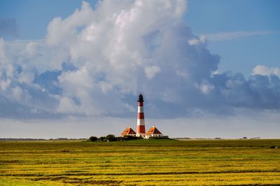 Lighthouse on field against sky