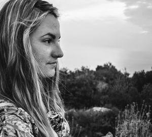 Side view of young woman against sky