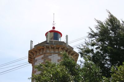 Low angle view of lighthouse by building against sky