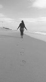 Rear view of woman walking at beach