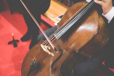 Midsection of man playing cello during performance