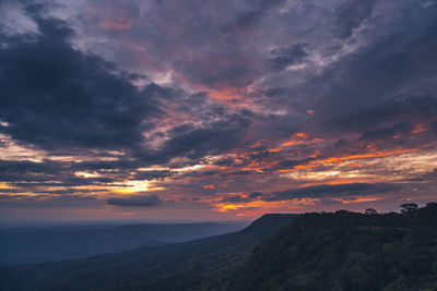 Scenic view of dramatic sky over silhouette mountains during sunset