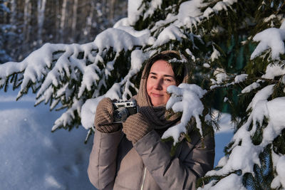 Young woman holding vintage old camera photographing winter nature