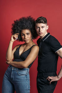 Stylish diverse girlfriend and boyfriend posing in a studio shooting with red background