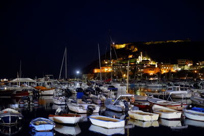 Sailboats moored in harbor at night