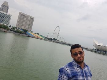 Portrait of man standing by river against sky