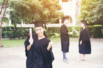 Cheerful student with clenched fist wearing graduation gown