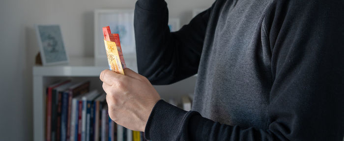 Midsection of man holding money at home