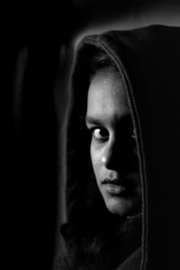 Close-up portrait of a young woman over black background