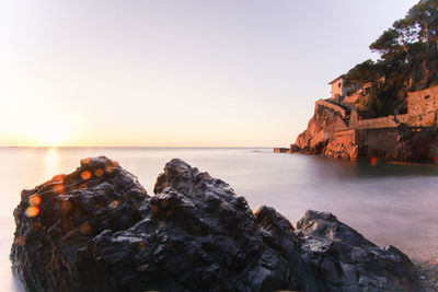 Rocks on beach against sky during sunset