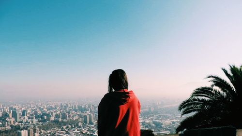 Rear view of woman looking at cityscape against sky