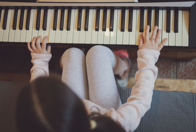 A little girl plays the electric piano.