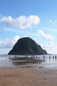 Group of people at beach against clear blue sky