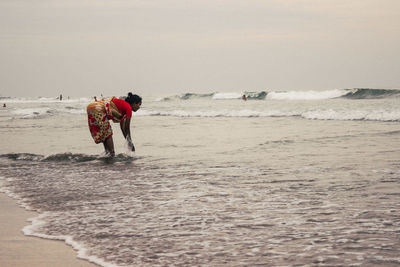 Rear view of men walking on beach against sky