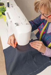 High angle view of woman sewing fabric over machine at home