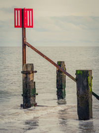Lifeguard hut on wooden post in sea against sky