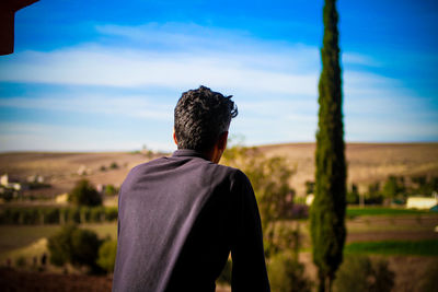 Rear view of man looking at landscape against sky on sunny day