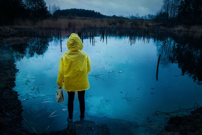 Rear view of woman standing by lake