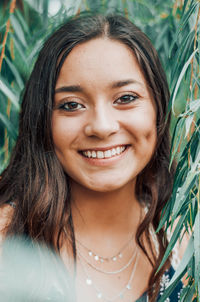 Close-up of a smiling young woman standing amidst plants outdoors