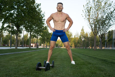 Rear view of shirtless man exercising in park