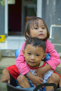 Portrait of cute girl with brother embracing outdoors