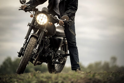 Low section of man riding motorcycle on field