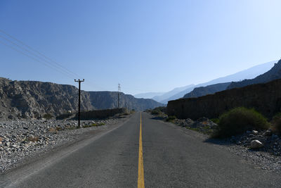 Road leading towards mountains against clear sky