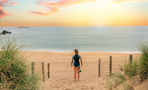 Surfer woman with wetsuit and surfboard looking at the sea