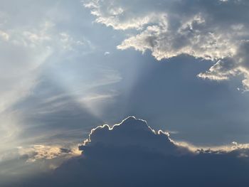 Low angle view of sunlight streaming through clouds