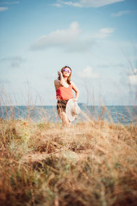 Full length of young woman on land against sky