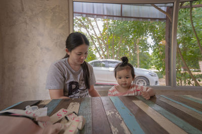 Mother and daughter sitting on table