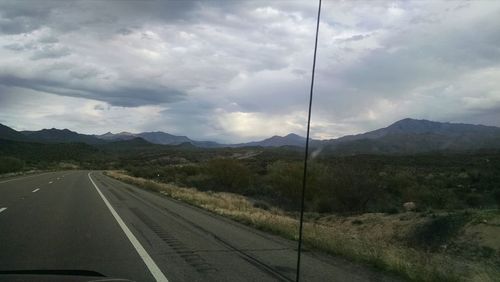 Road by mountains against sky