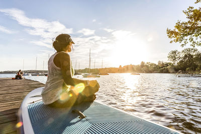 Woman sitting on boat in river against sky